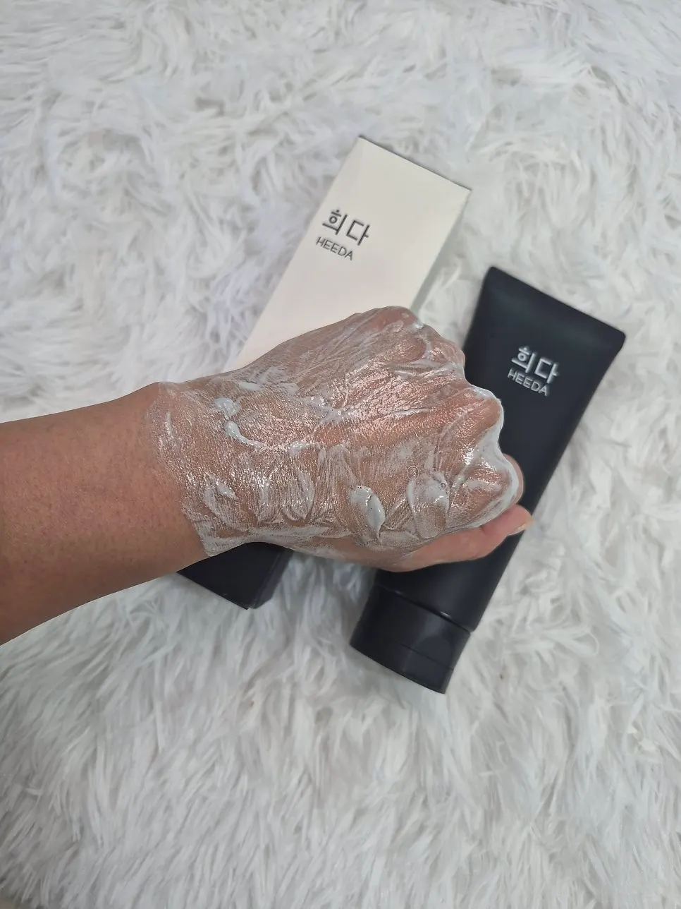 Black foaming cleanser texture dispensed onto the back of a hand