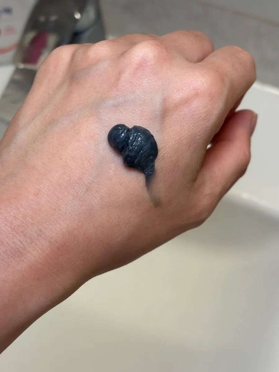 Deep gray foam cleanser texture squeezed onto the back of a hand