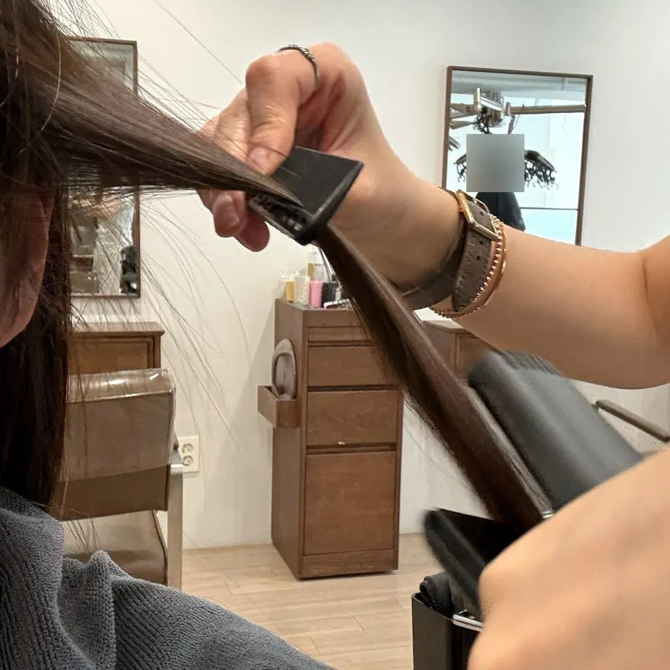 Straightening hair with a flat iron during the root magic process
