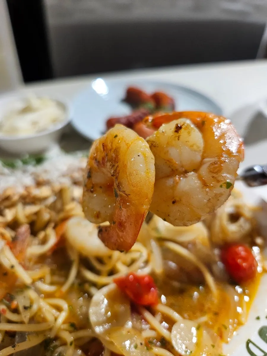 Shrimp tomato oil pasta topped with garlic chips and parmesan