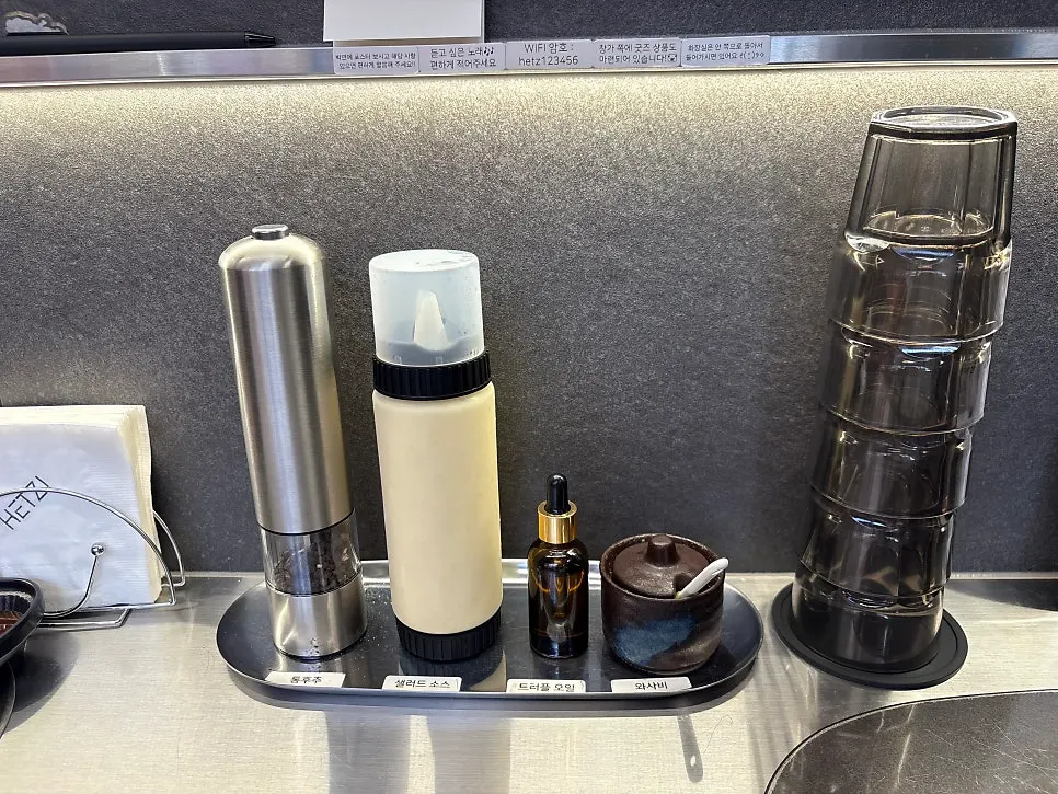 Table with whole black pepper, salad dressing, truffle oil, and wasabi