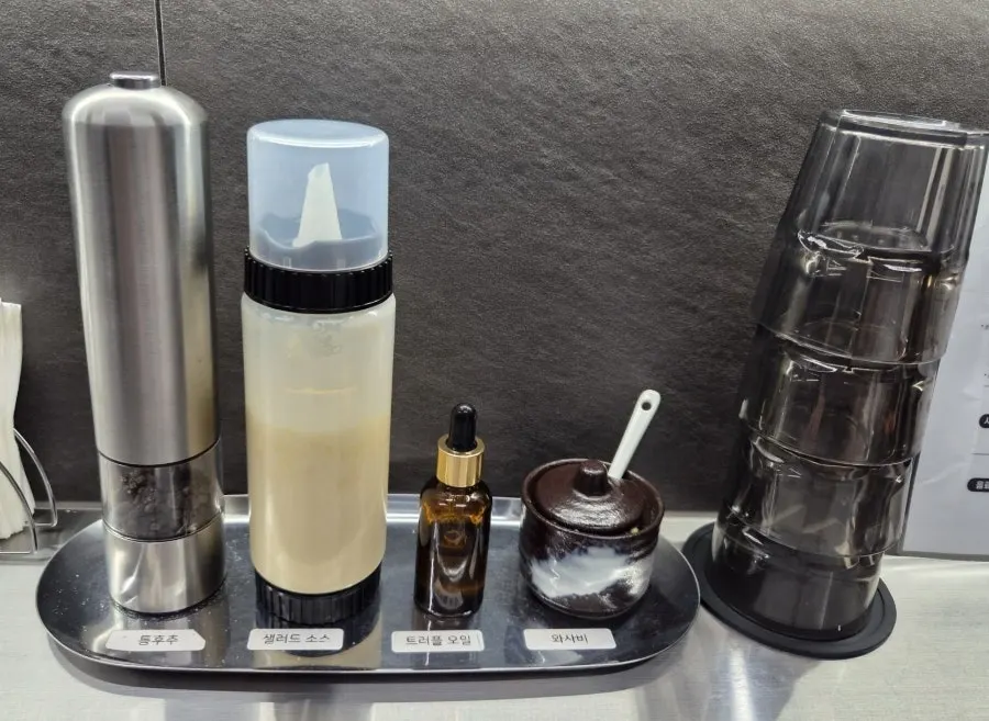 Condiment stand with whole black pepper, salad dressing, truffle oil and wasabi