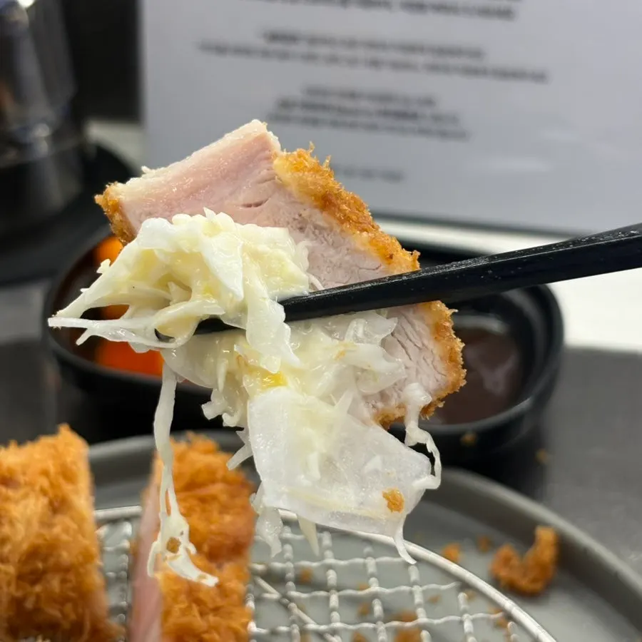 A piece of sang loin katsu dipped in sauce