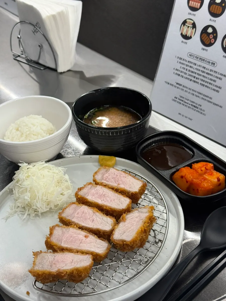 Chopsticks holding a cross-section of Jeju black pork loin katsu
