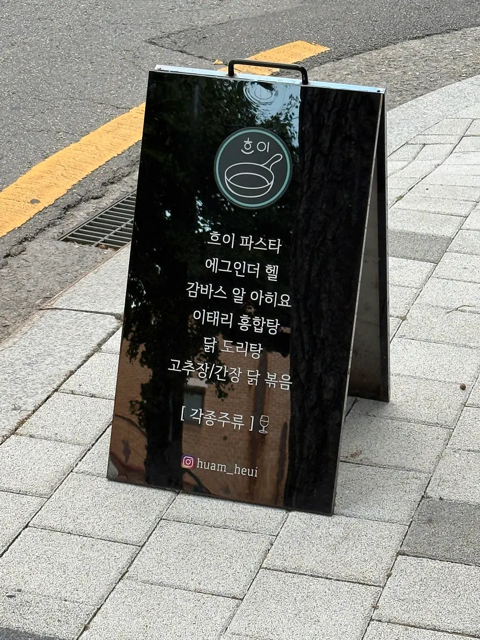 Black standing signboard with menu items in front of Heui's entrance