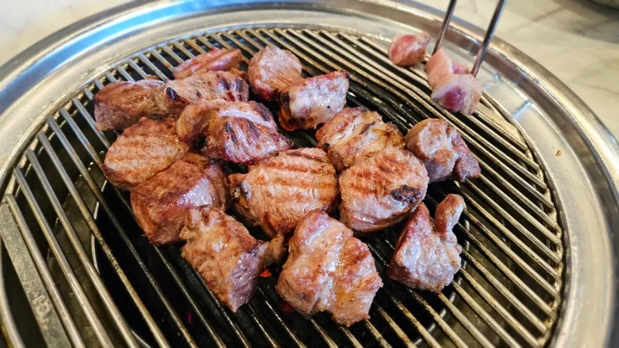 A piece of grilled black pork neck placed on a small plate