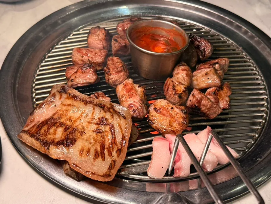 연탄 불판에 올린 초벌 목살과 돼지껍데기