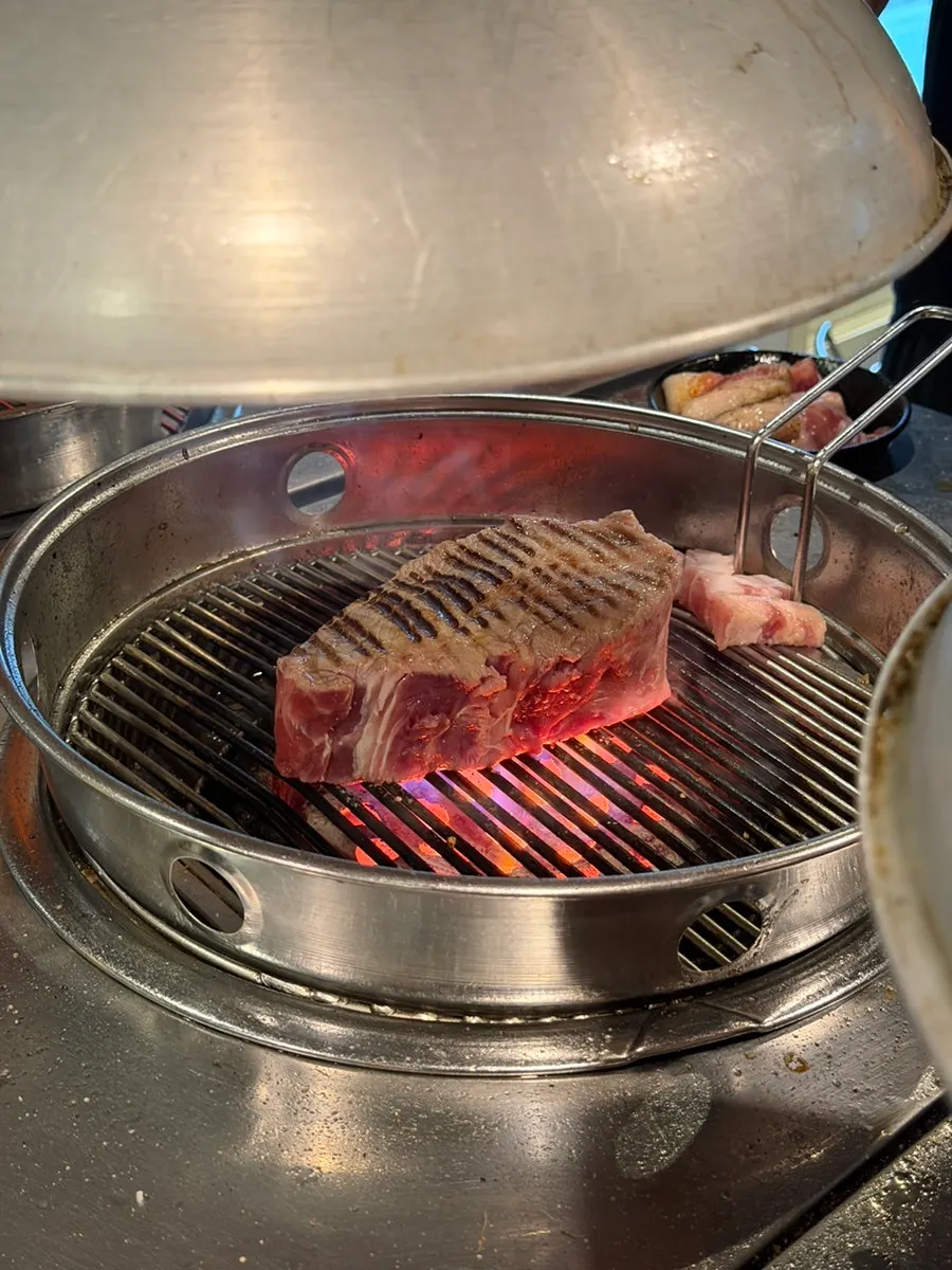 Leher babi dipanggang di zona grilling dengan briket arang