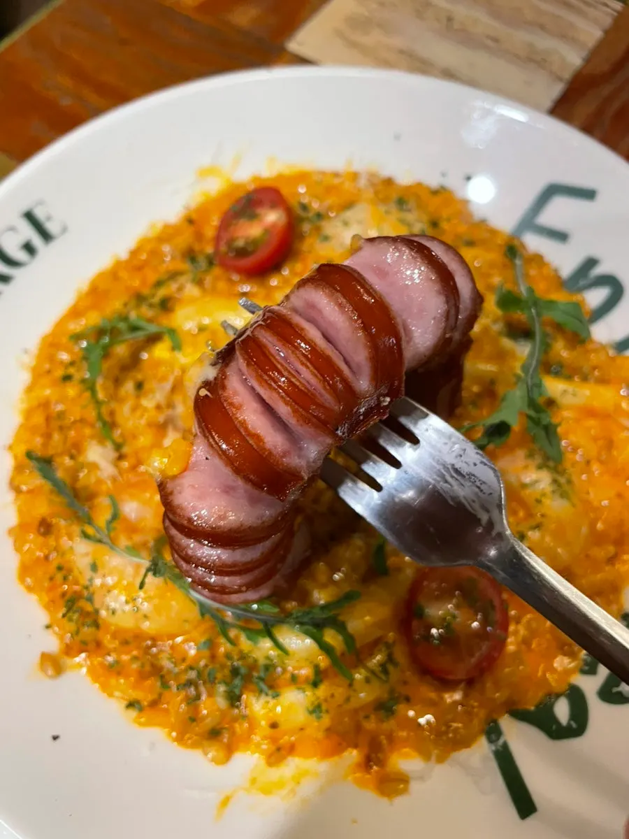 Plump whole sausage on top of the risotto
