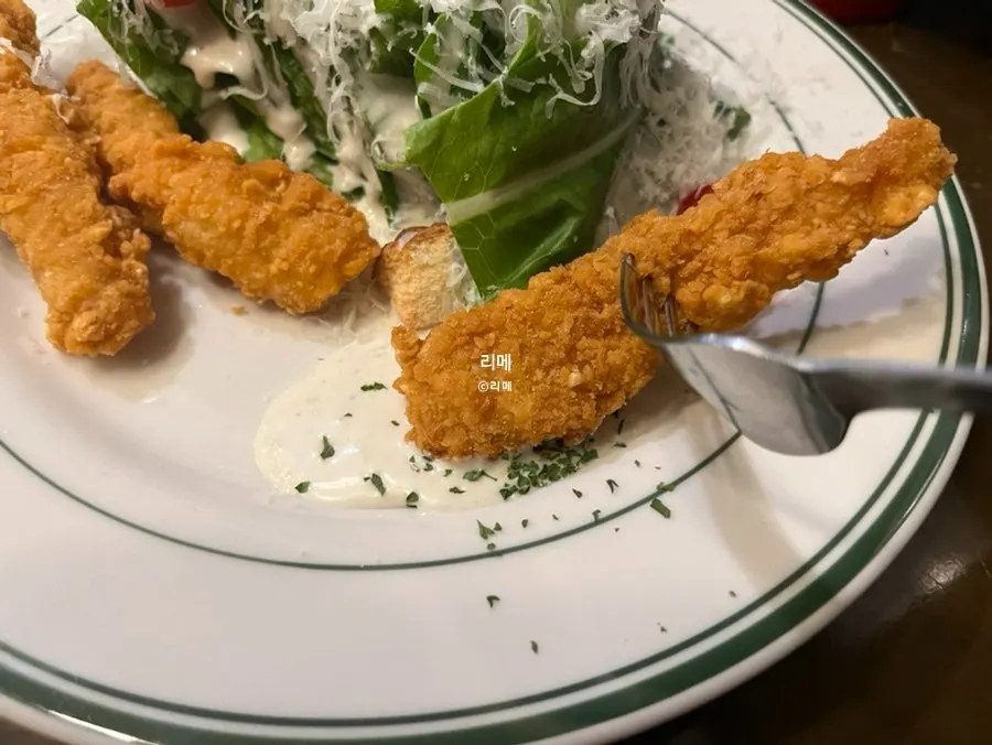 Generous Caesar-style sauce spread across the plate with chicken tenders