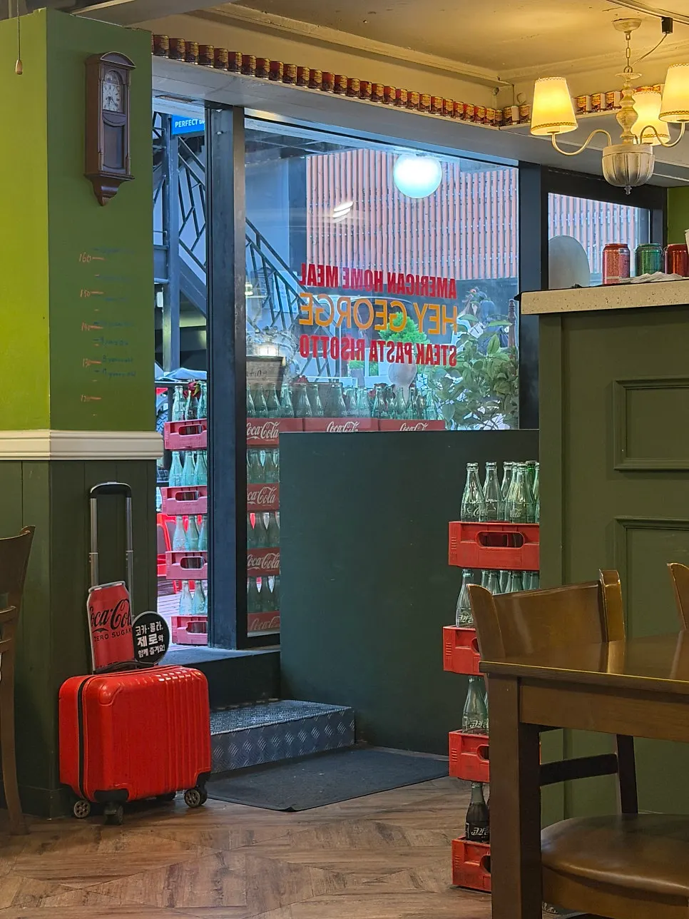 Stacked Coke crates and a red suitcase prop at the entrance