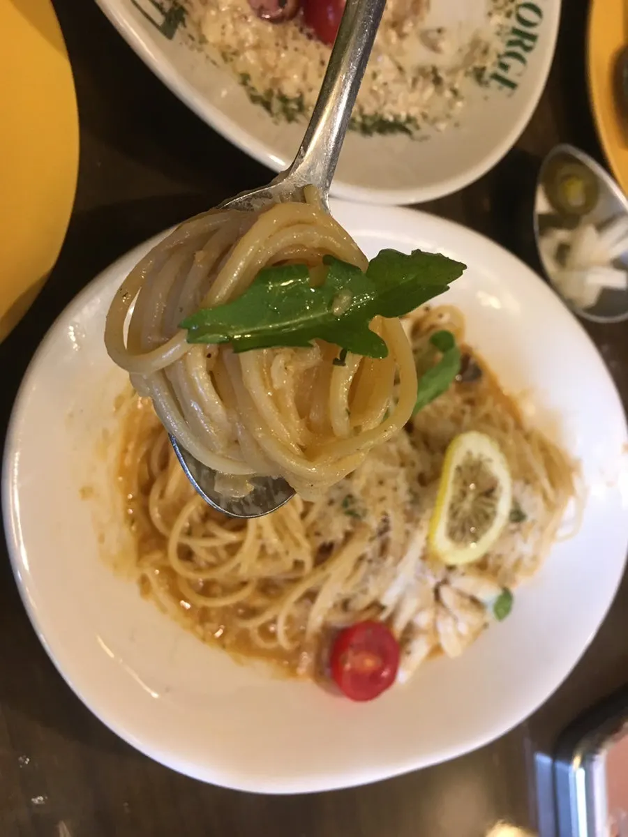 Close-up of garlic oil pasta topped with squid