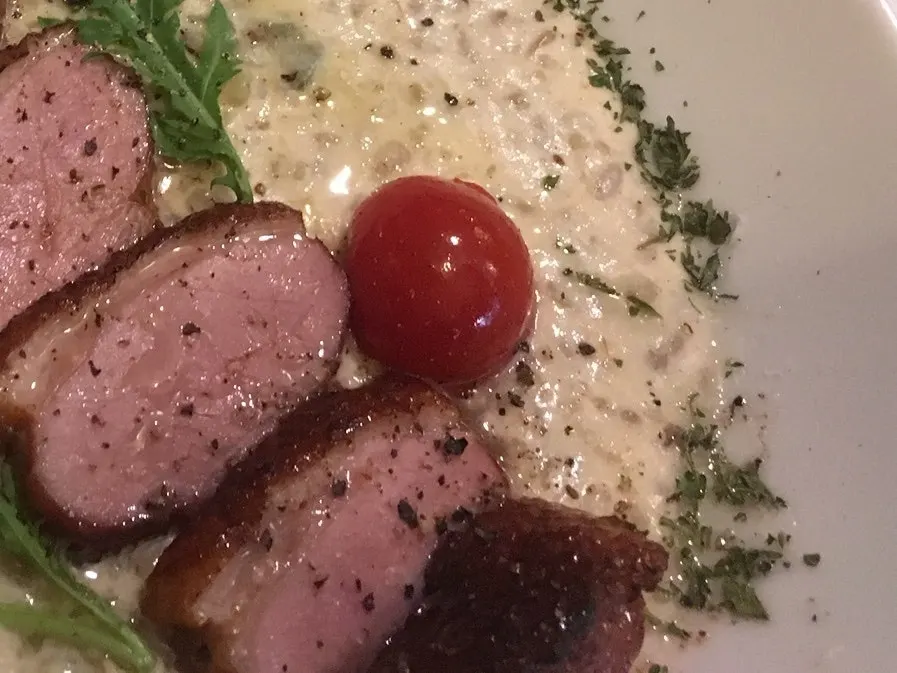 Cross-section of duck steak on top of the cream risotto