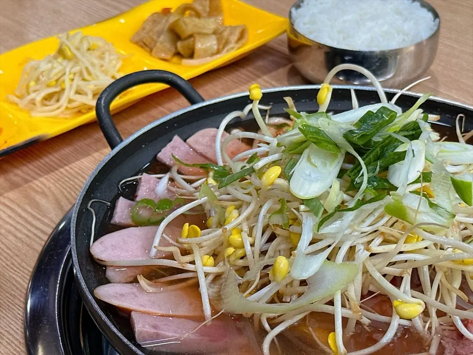 Table setting of seasoned bean sprouts, stir-fried fish cake, and kimchi side dishes