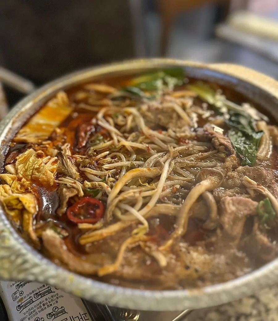 A scoop of broth and fillings from the mala hot pot