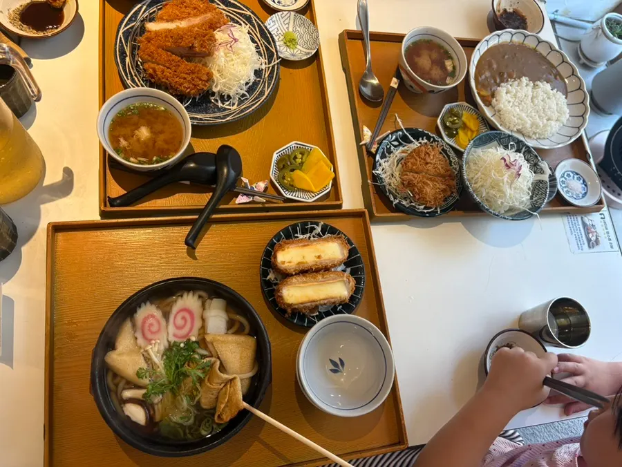 Bàn ăn đầy ắp với set tonkatsu, cà ri và udon
