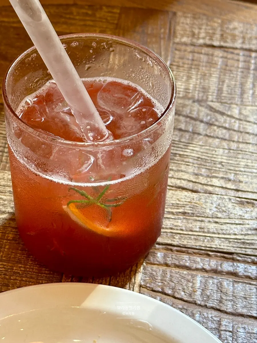 A glass of plum ade being stirred well before drinking
