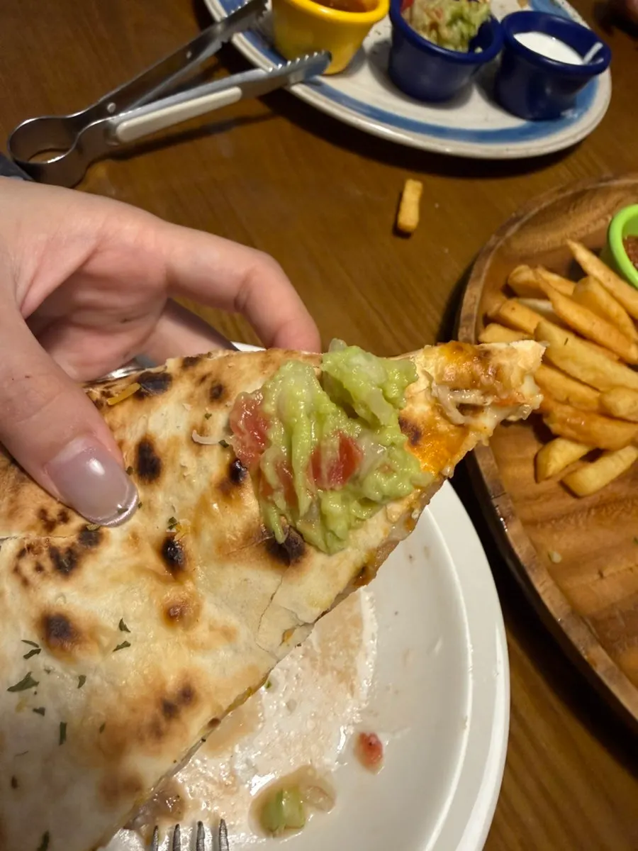 A bite of chicken quesadilla with a crisp tortilla