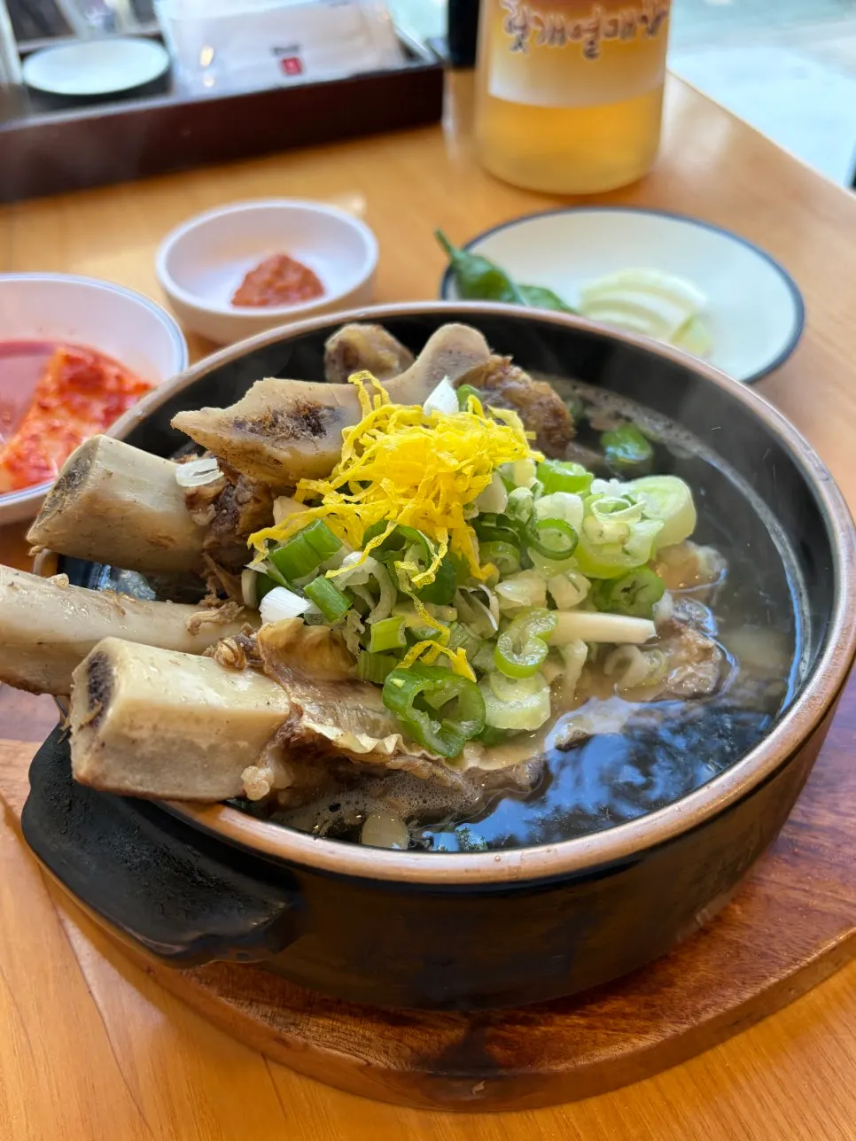 Earthenware bowl of Teuk Wang Galbitang topped with short rib bones and egg garnish