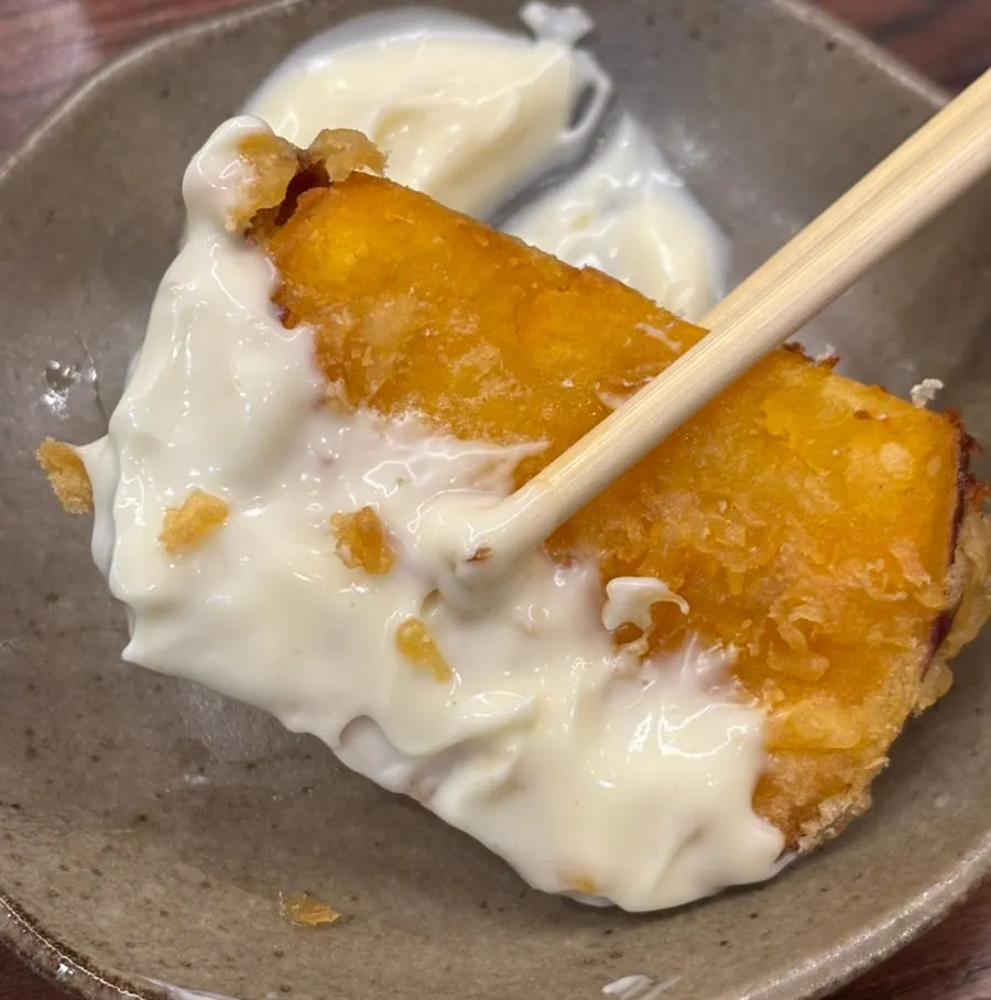 Sweet potato fritter being dipped into mayo sauce