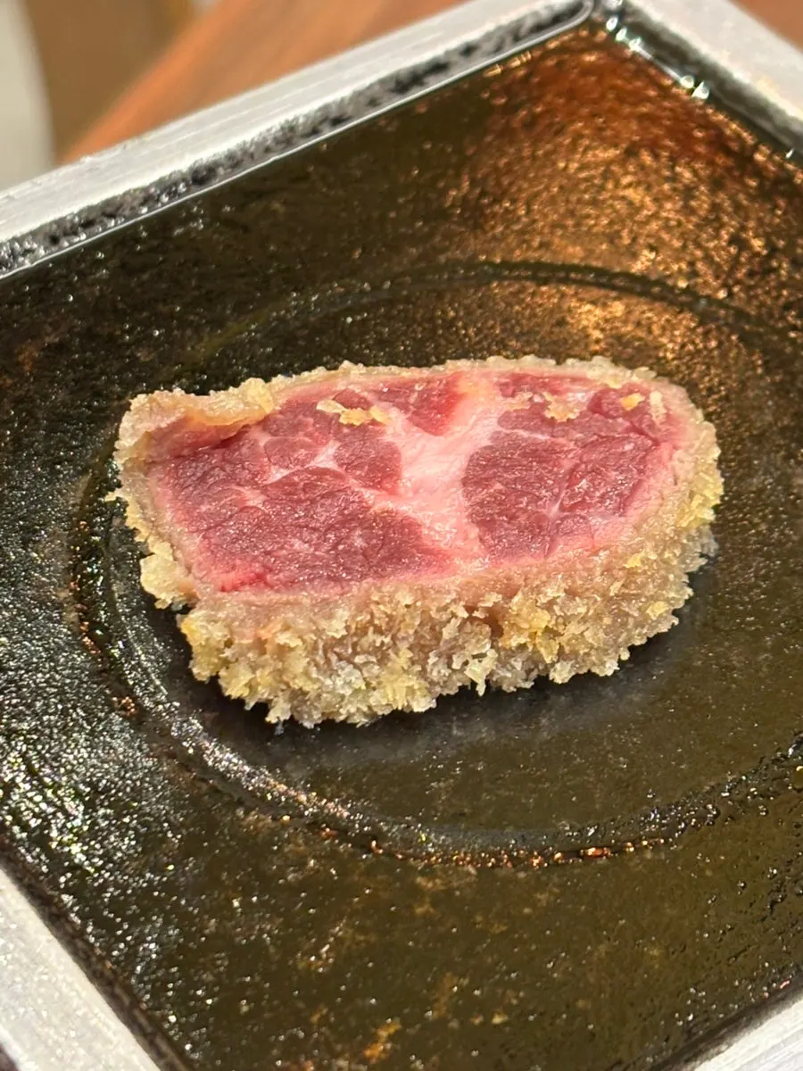Pieces of gyukatsu cooking on the grill