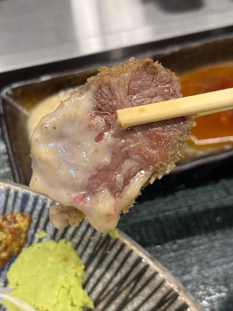 A piece of gyukatsu being dipped in sauce