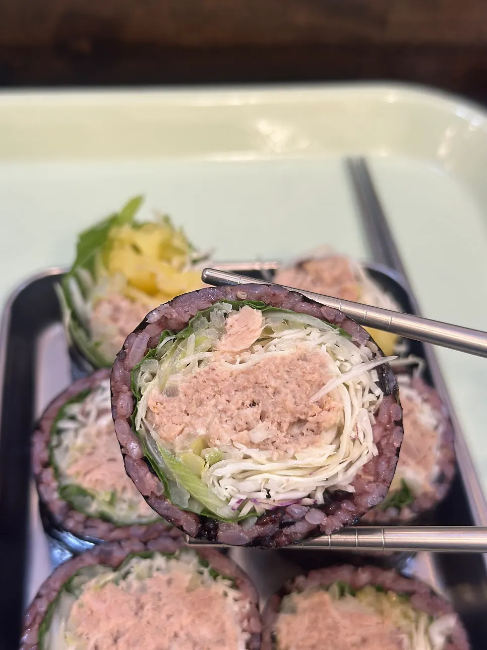 Cross-section of black rice Jindo green onion tuna gimbap packed with filling