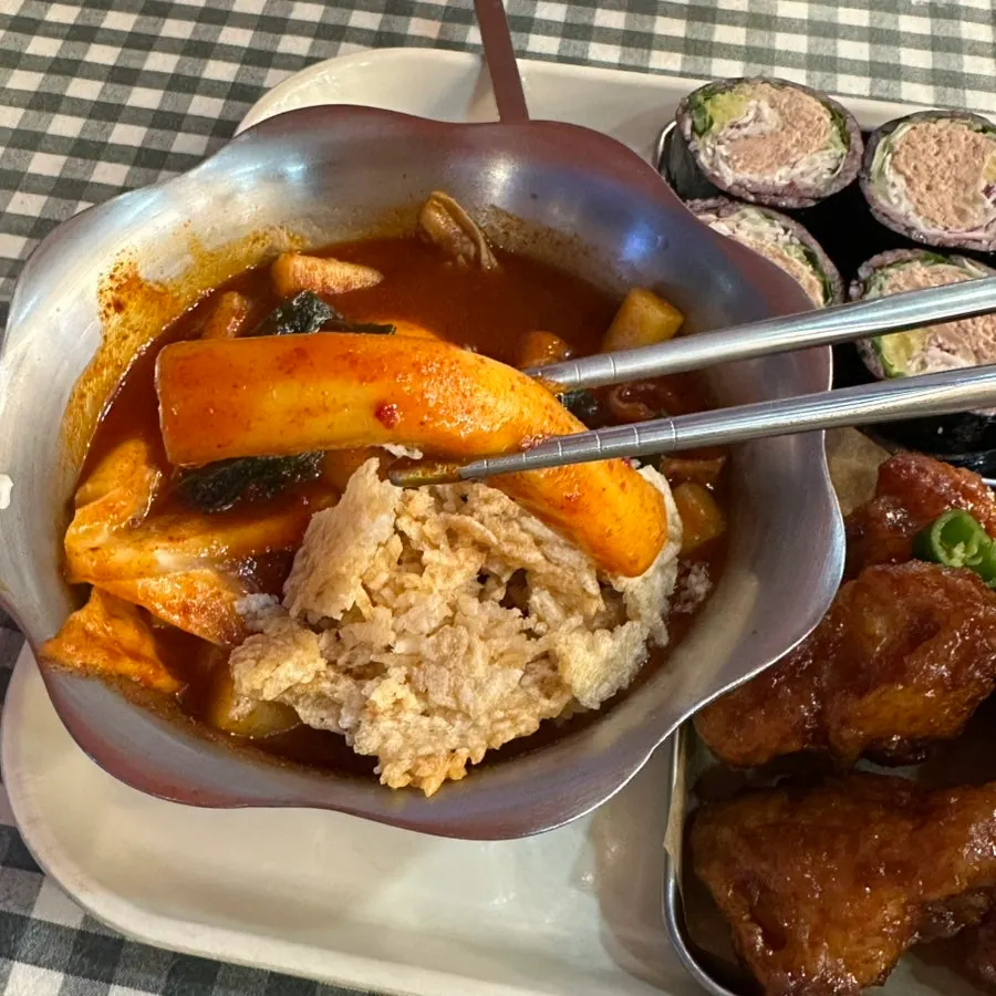 떡볶이 소스가 스며든 밀떡을 집어 든 모습