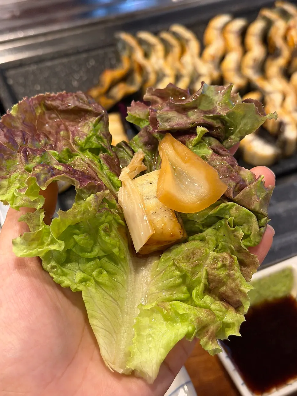 A piece of eel with special sauce, wasabi, and onion