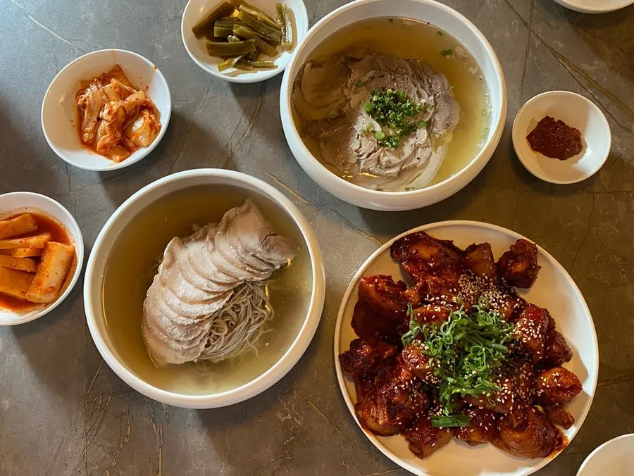 Table spread of Pyeongyang naengmyeon, gomtang, and pork tail jjim