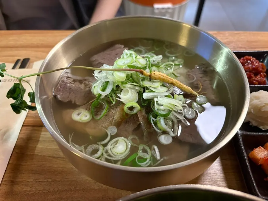 A bowl of beef gomtang topped with ginseng