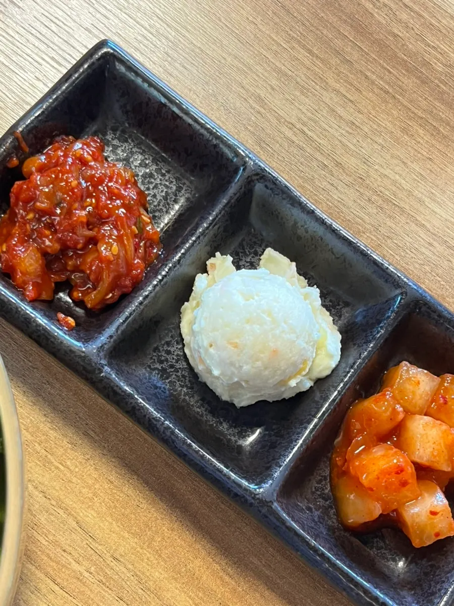 Three side dishes: salted seafood, potato salad, and kkakdugi