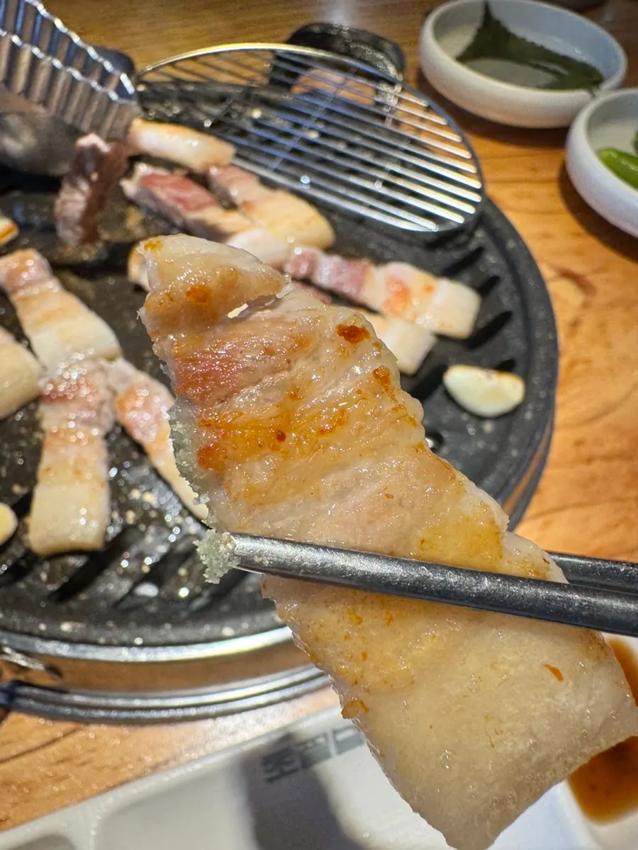 Grilled salted ogyeopsal piece dipped in salt
