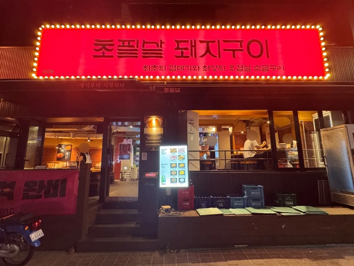 Red signage of Chopilsal Pork Grill Hongdae Branch in a Hongdae alley