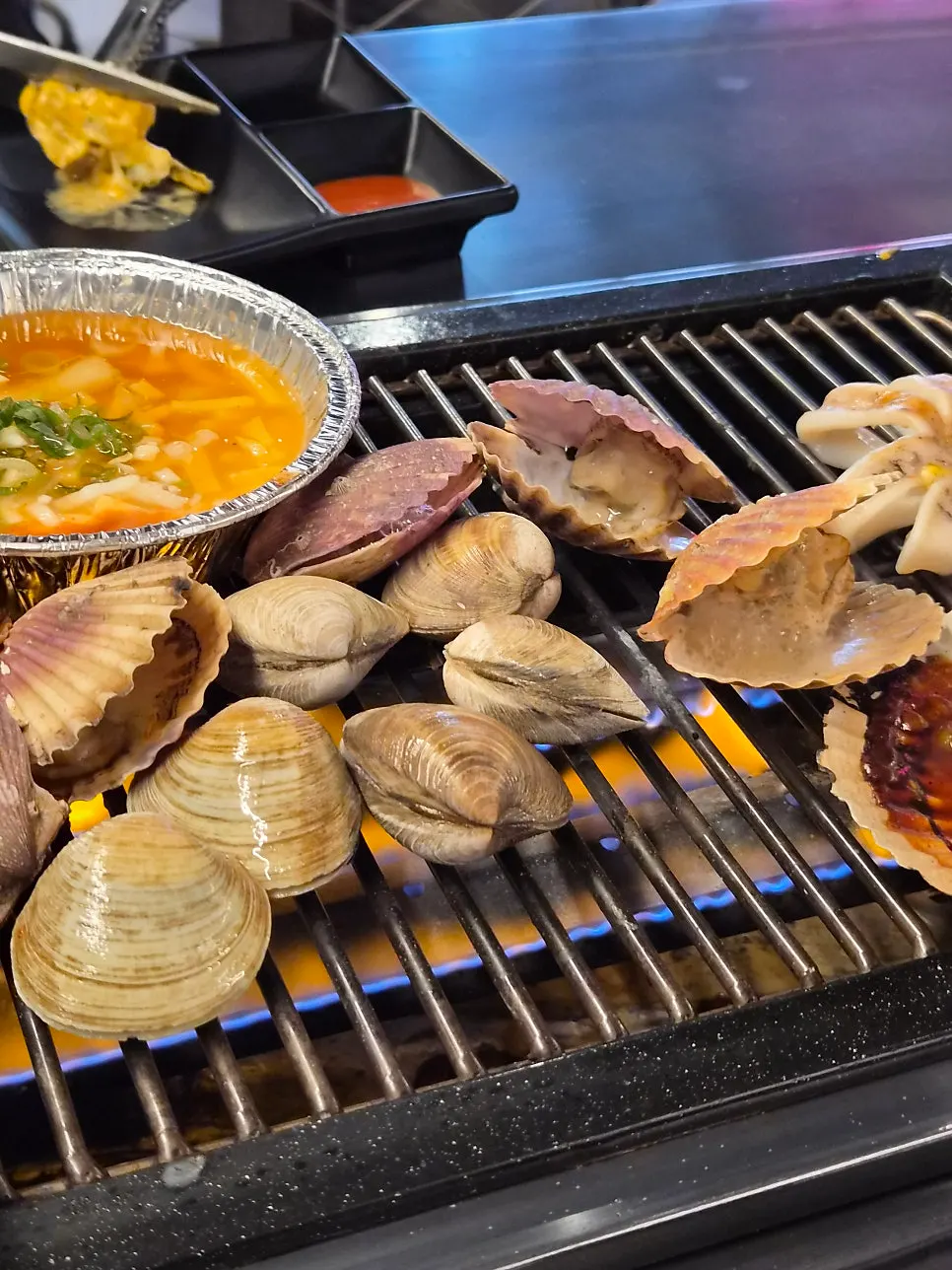 Clams and whole scallops grilling on the plate