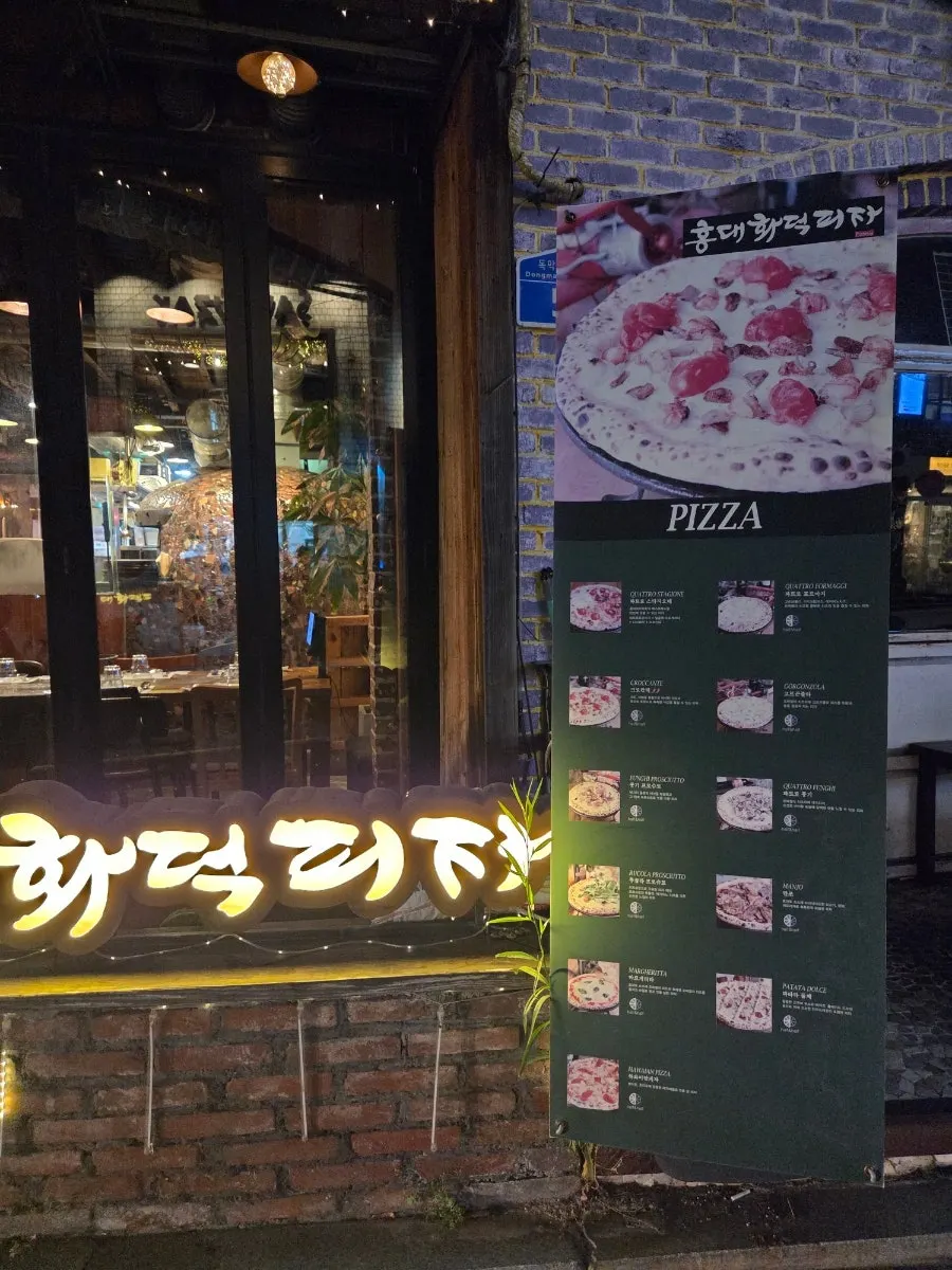 Menu board showing pizza and pasta options at Hongdae Hwadeok Pizza