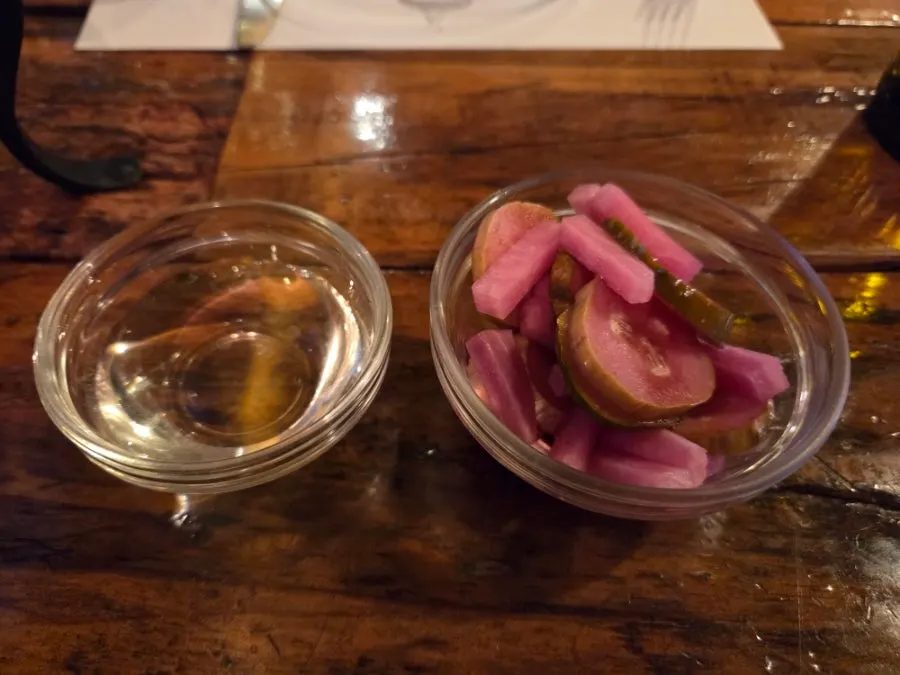 Honey and pickles served alongside the pizza