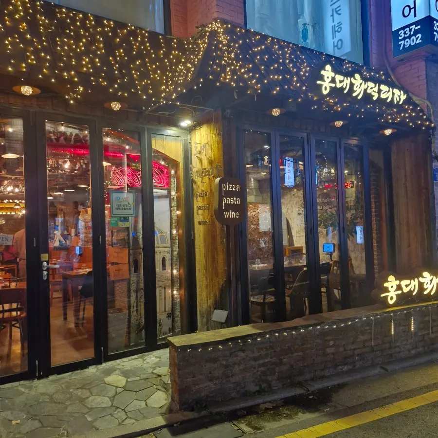Exterior of Hongdae Hwadeok Pizza on the ground floor of a Dokmak-ro alley near Hapjeong Station