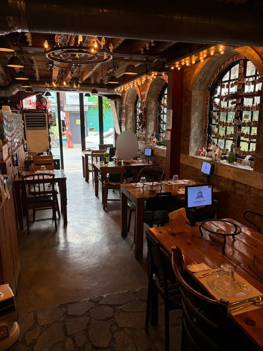 Interior of Hongdae Hwadeok Pizza with wood, brick, and soft lighting