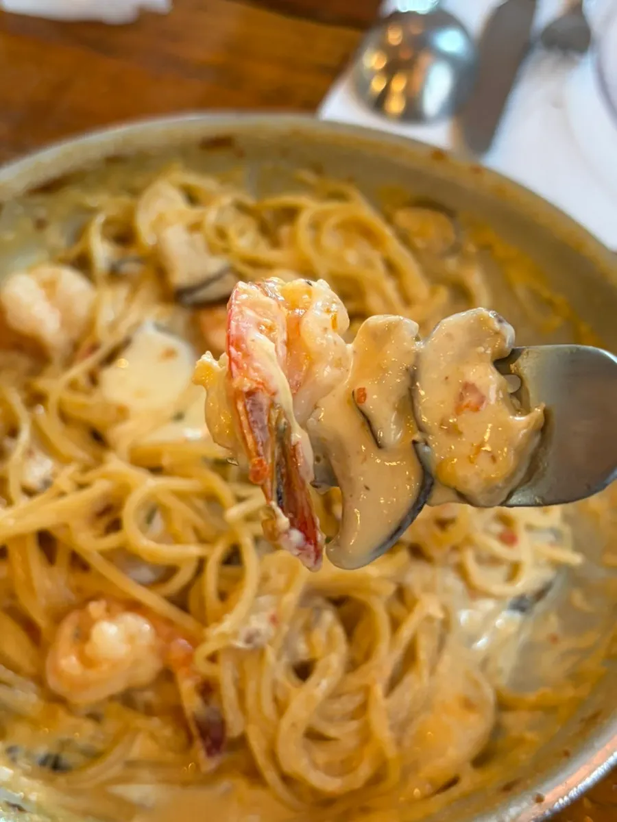A forkful of shrimp cream pasta lifted up