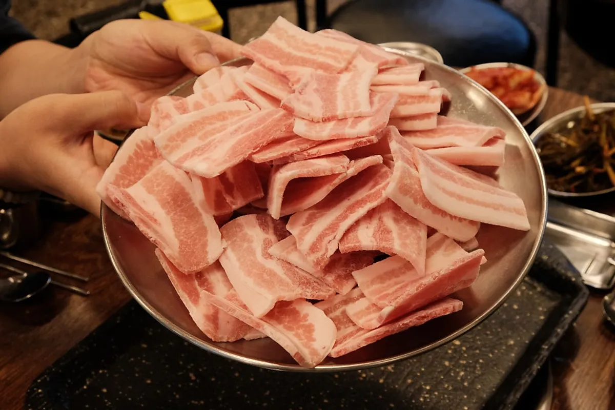 마포구이마당 서교직영점 불판 위 냉동삼겹살과 미나리