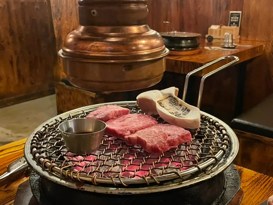 직원이 숯불에 고기를 구워주는 장면