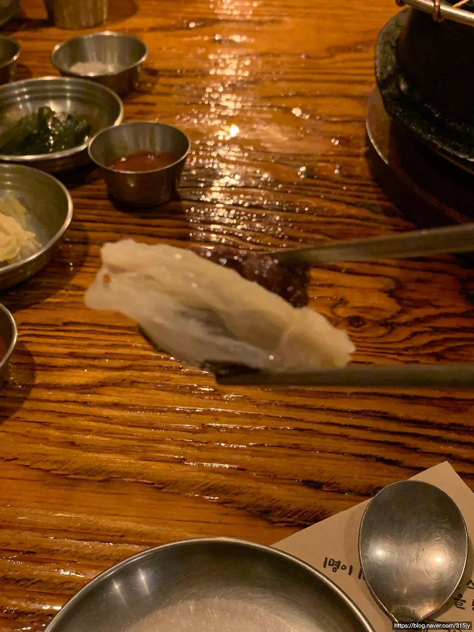 Table setting with braised onion, green onion kimchi, myeolnamul, white kimchi, and myeoljeot side dishes
