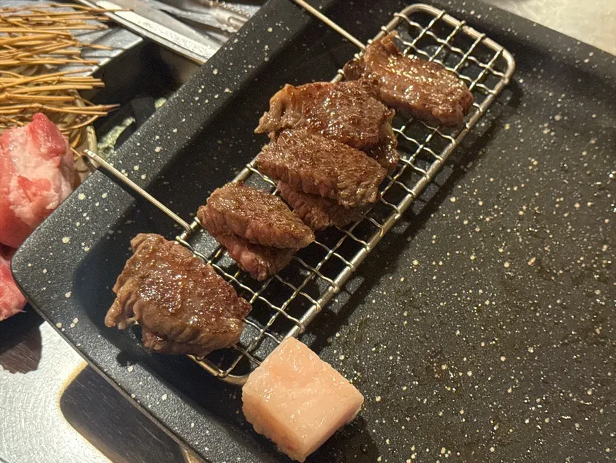 Beef skirt being coated with fat trimmings while grilling