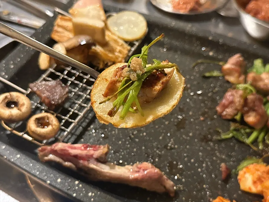 A piece of grilled meat placed on top of potatoes