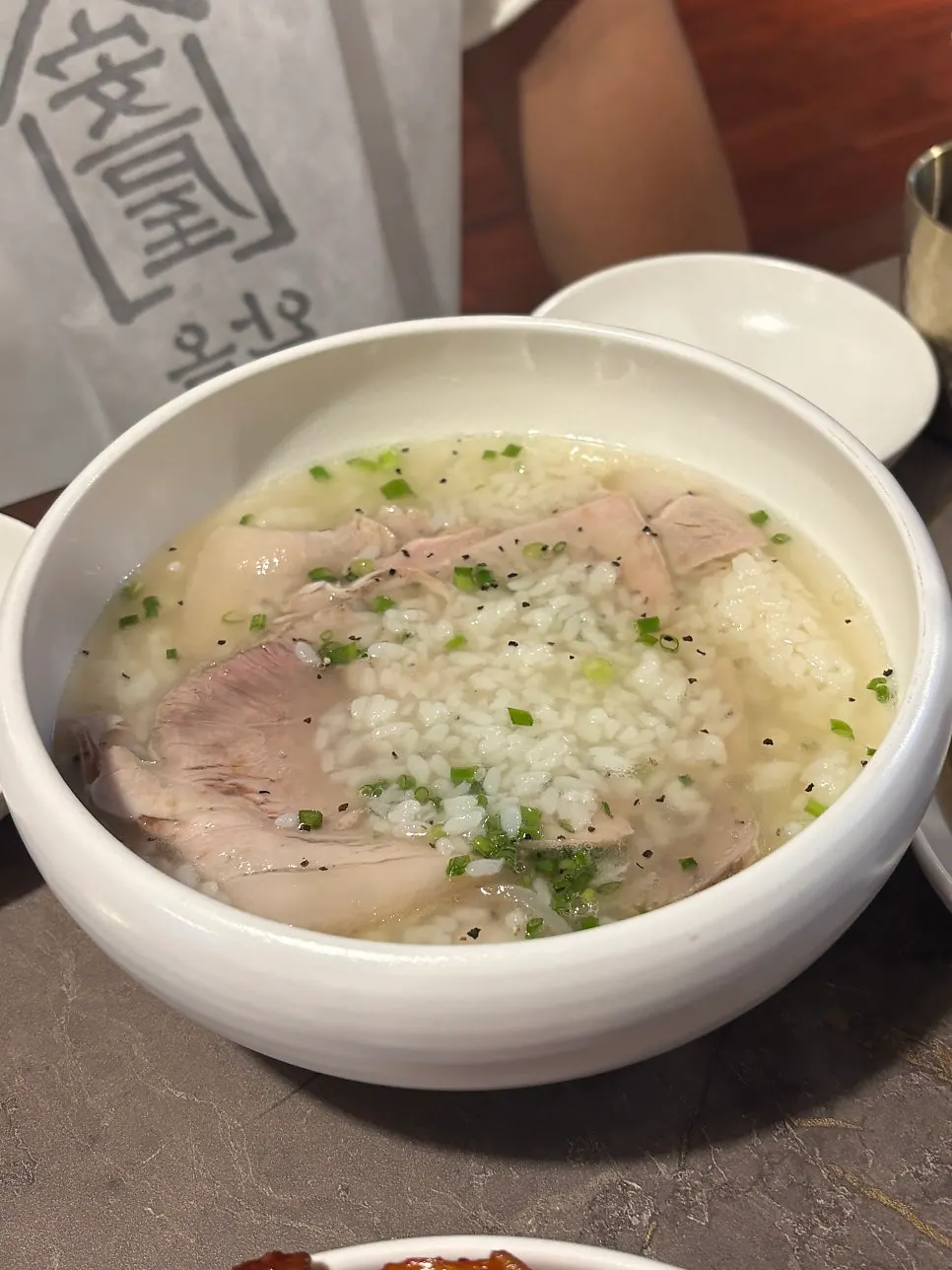 Clear gomtang topped with whole peppercorns and scallions