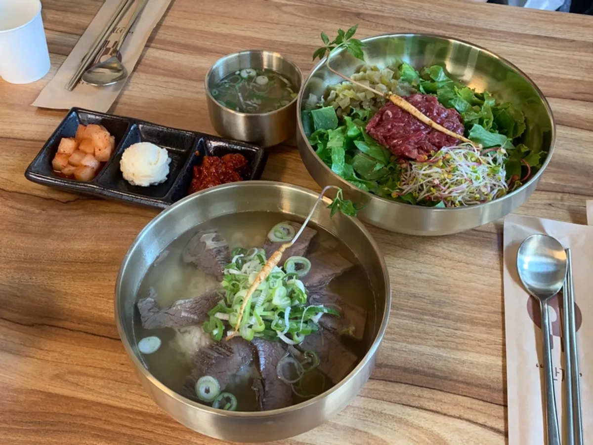 A bowl of beef gomtang topped with sprout ginseng
