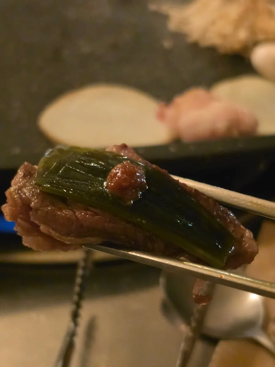 A piece of skirt steak topped with wild garlic leaves and ssamjang