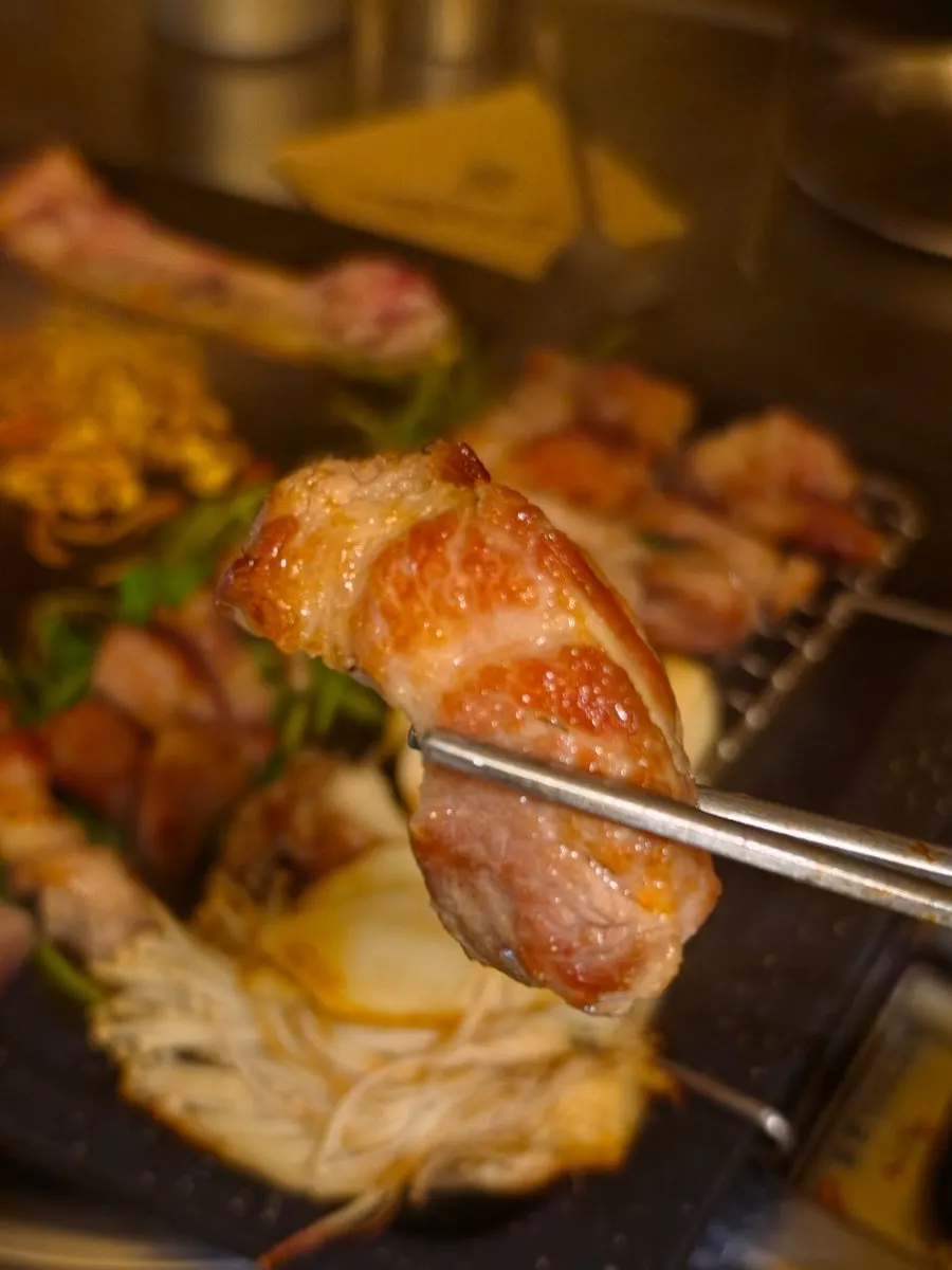 A completed grill spread with meat, minari, and kimchi
