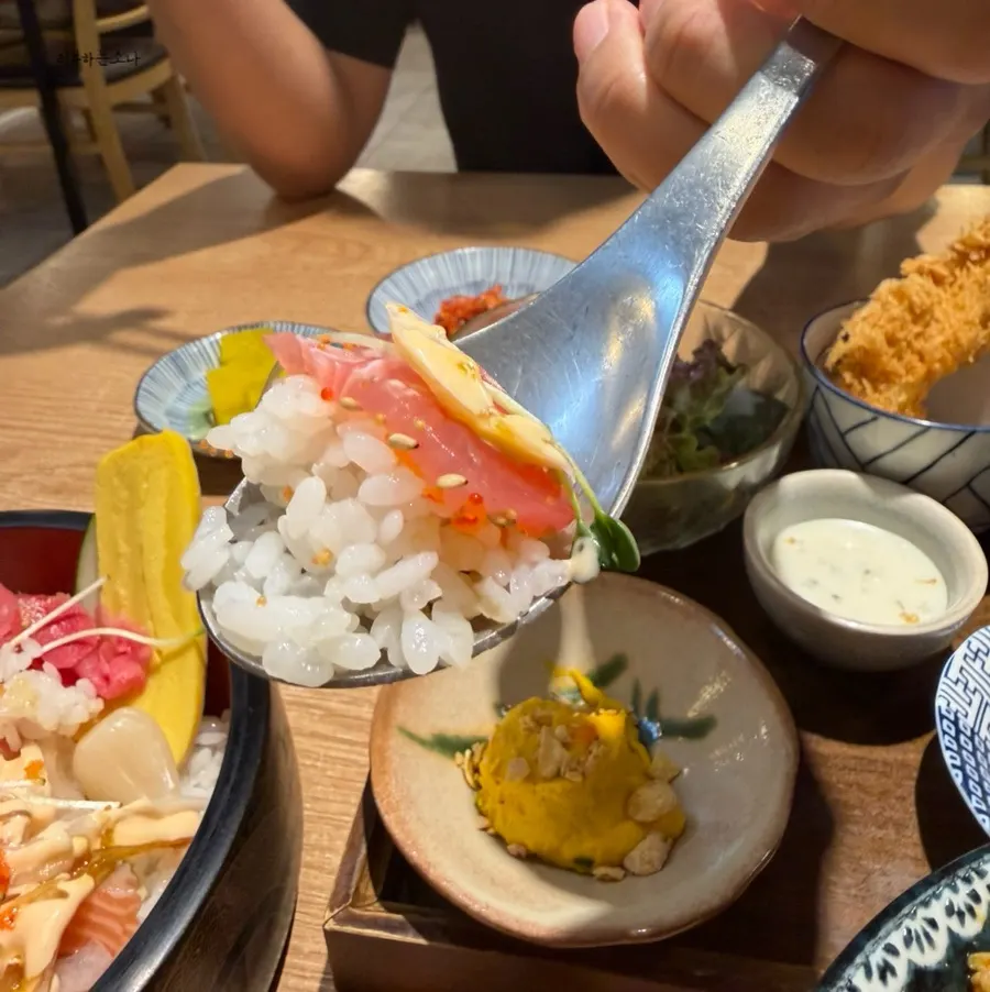 A spoonful of scooped sushi lifted from the bowl